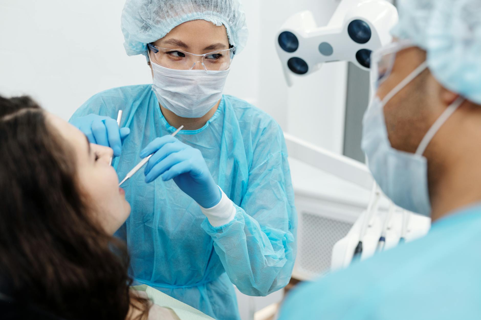 Dentysta w maseczce bada zgryz pacjenta w nowoczesnym gabinecie