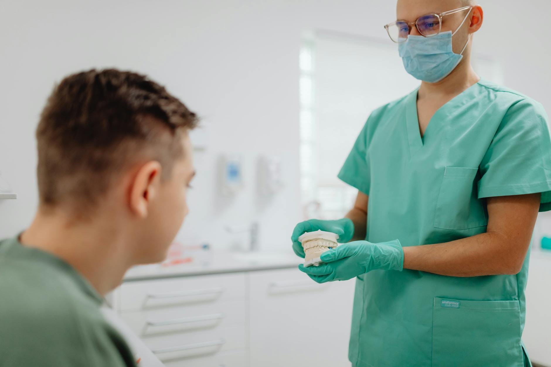 Dentysta omawia retencję po prostowaniu zębów z pacjentem przy modelu