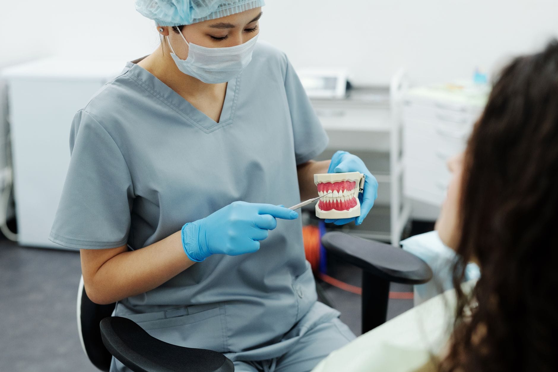 Dentysta pokazuje pacjentowi model zębów podczas instruktażu higieny