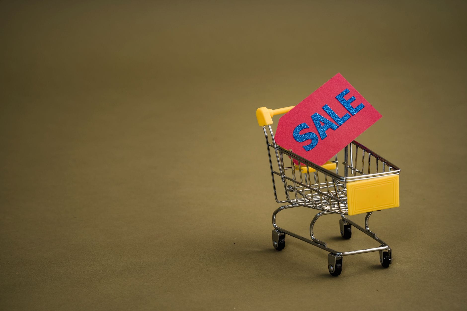 Miniaturowy wózek sklepowy z czerwonym napisem SALE na brązowym tle